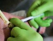 Hände von Ärztin mit grünen medizinischen Gummihandschuhen halten Injektionsnadel im Arm von Patientin bei Blutabnahme in Arztpraxis