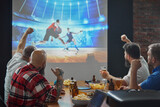 Fototapeta Sport - Men, friends sitting at table with beer and snacks, watching online basketball game translation on TV and cheering up favorite team. Concept of sport, championship, game, sport fans, leisure