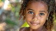 children of mauritius, A portrait of a young girl with curly hair and a bright smile in a natural setting looking at the camera with innocence and joy. 