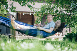 Fototapeta  - A man is resting and reading in a hammock. Day off and relaxation
