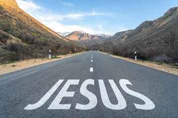 Wall Mural - Asphalt road surrounded by mountains, Jesus written on the road. Christian concept. Jesus is the way