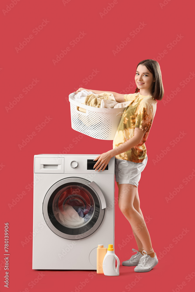 Young woman with laundry basket and washing machine on red background