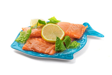 Wall Mural - Salmon filet on a blue fish shaped plate with lemon slice and garnish ready to be cooked isolated on white