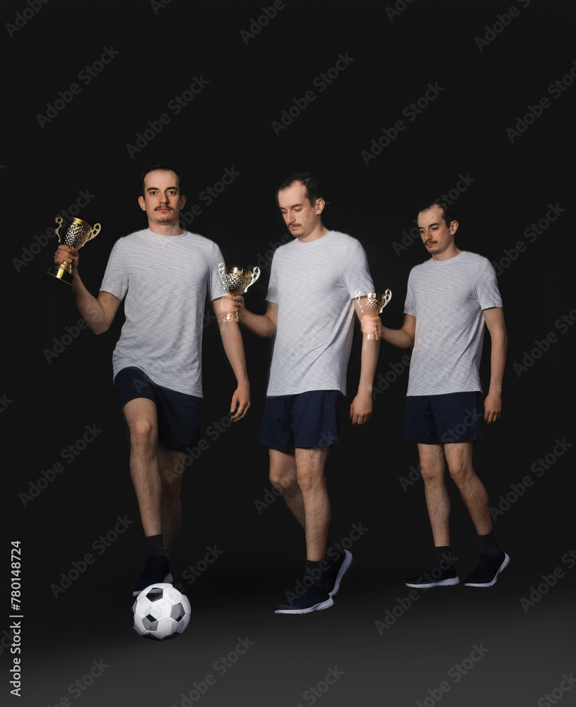 Handsome man with gold cup and ball in motion on black background