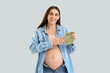 Young pregnant woman with calculator on light background. Maternity Benefit concept