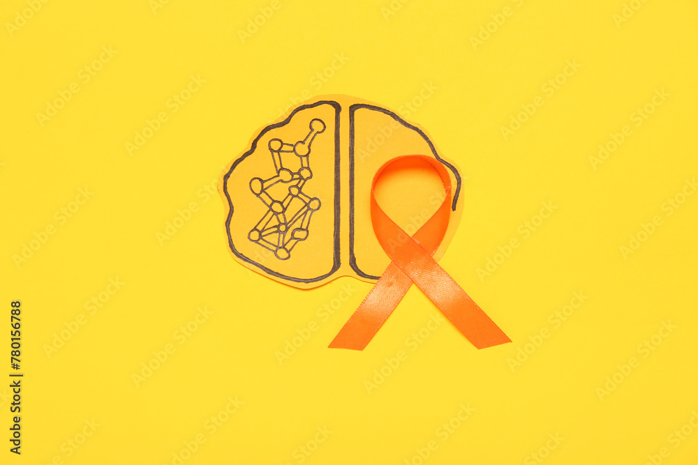 Paper brain with orange ribbon on yellow background. Multiple Sclerosis Awareness Month