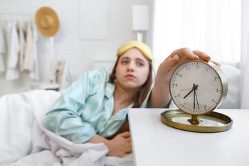 Canvas Print - Young woman turning off alarm clock in bedroom, closeup