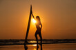 Silhouette sexy beautiful Asian model wearing bikini swimming suite posing happy on beach with surfboard is water sport game and hobby leisure in summer holiday lifestyle with sunset sky background.