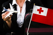business woman holds toy plane travel bag and flag of Tonga
