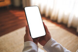 Fototapeta  - Mockup image of a woman holding mobile phone with blank desktop white screen at home