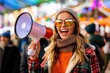 © apratim - Joyful young woman in trendy autumn fashion smiling and making an announcement with a megaphone at a festive outdoor event.