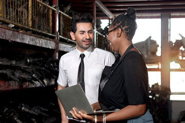 Wall Mural - Happy harmony people at workplace, smiling white guy and African American woman working together Two workers check stock at auto spare parts store shop warehouse, surrounded by secondhand engine parts