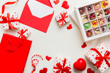 Wall Mural - top view photo of st valentine day decor shopping, bag, envelope, gift, box, candy and red heart on colored background with empty space. Frame background