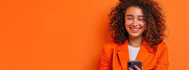 Canvas Print - Portrait of smiling african american woman using smartphone isolated on orange background, wearing red sweater with copy space for your text message or promotion banner.