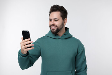 Wall Mural - Happy young man using smartphone on white background