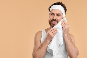 Wall Mural - Washing face. Man with headband and towel on beige background, space for text