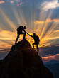 Silhouette of two people helping each other to reach mountain top, achievement and determination concepts