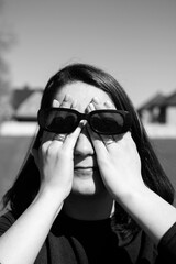 Wall Mural - Conceptual portrait of a woman in sunglasses. Young attractive woman covering her face with a her hands	