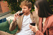 A man and a woman enjoy a cozy evening on a couch, sipping wine together
