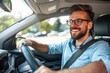 © ttonaorh - Handsome young man is driving a car and smiling driving a car with a clear view of the city through the window. showcasing safe driving with a seatbelt