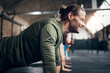 © Flamingo Images - Smiling man doing push-ups during a workout class at the gym. His friends next to him are also doing push ups.