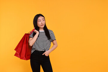 Canvas Print - Beautiful woman with shopping bags on yellow background. Space for text