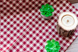 checkered red and white tablecloth with two green decors and one wooden candle. Free place for logo and text