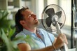© gankevstock - Office worker seeking relief from heat with a desktop fan