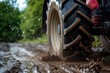 A tractor wheel driving on muddy road. Agricultural machinery splashing mud. Sleet. Climate. Soggy soil. Environmental awareness. Farmer equipment. Copy space. A tire of the tractor in mud. Drips