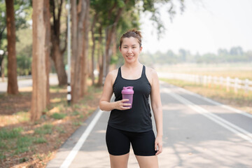 Asian woman drinking water after exercising. Taking care of your figure and staying healthy.