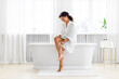 Woman with crossed legs sitting at tub edge