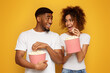 Positive african man and woman eating popcorn