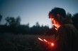 © Wirestock - Young Caucasian male looking at his smartphone with a red light reflecting on his face in a field