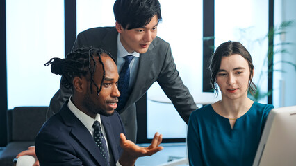 Poster - Multinational businesspeople talking while looking at PC monitor in the lobby. International business.