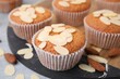 Muffins with fresh almond flakes and nuts on grey table, closeup
