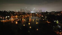 Glowing Swan Pedal Boats On Echo Lake With The Los Angeles City Skyline - Aerial Flyover