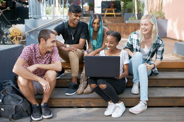 Happy, students and outdoors with laptop on stairs for learning, education and online research for project. Diversity, friends and group with technology for discussion, teamwork and study session