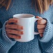 © Margo_Alexa - A woman in a blue sweater holding up a white mug