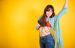 Joyful Young Woman Dancing and Listening to Music on Yellow Background