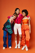 © LIGHTFIELD STUDIOS - A group of multicultural women, including Caucasian, Asian, and African American, stand together harmoniously against an orange background.