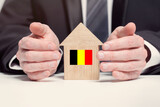 Fototapeta  - Businessman hand holding wooden home model with Belgium flag. insurance and property concepts