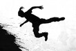 black silhouette of a man doing stunts on the ground