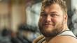 © iuricazac - A bearded man with a broad smile wearing a sleeveless top standing in a gym or sports facility with blurred background.
