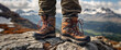 A hiker person wearing hiking boots is standing on a rocky mountain top. The scene captures the essence of adventure and exploration as the individual takes in the breathtaking view of the surrounding