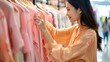 A stylish shopper trying on a coral shirt in a boutique, with the help of a fashion consultant, to create a trendy outfit based on the color of the upcoming year.