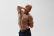Sculpted physique of serious-looking bald man with beard in power stance against grey studio background. Concept of men's health, self care, fashion and beauty, healthy lifestyle. Ad