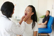 © DragonImages - Pediatrician asking girl to open mouth when checking her throat
