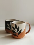 Fototapeta Natura - Handcrafted ceramic mugs with elegant leaf designs, ideal for a cozy coffee break or a stylish kitchen
