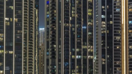 Wall Mural - Tall blocks of flats with glowing windows located in residential district of city aerial timelapse. Evening light in rooms of apartments in towers and illuminated skyscrapers