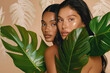 beautiful women with smooth skin, smiling and touching her face against the background of monstera leaves